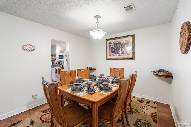 dining space with a textured ceiling and light tile patterned floors