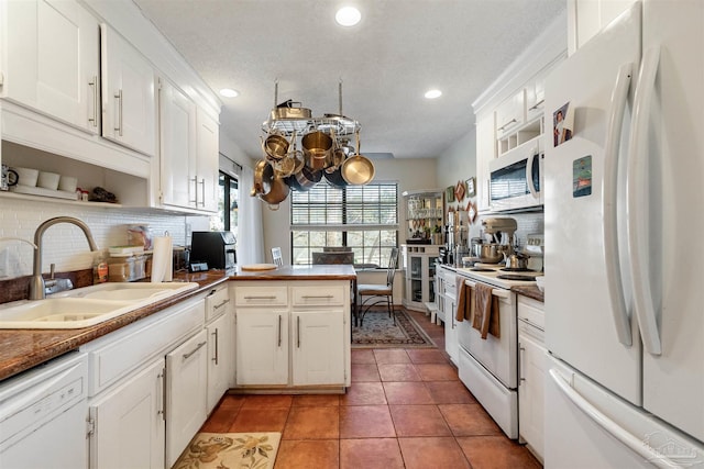 kitchen with sink, white appliances, white cabinetry, and kitchen peninsula