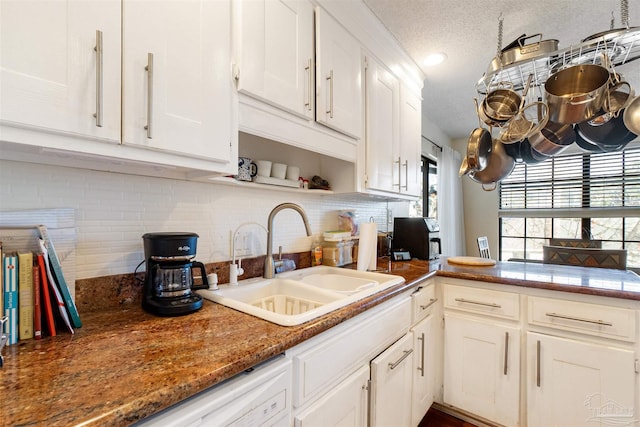 kitchen featuring sink, white cabinetry, dark stone countertops, tasteful backsplash, and kitchen peninsula