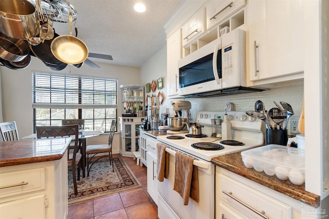 kitchen featuring white cabinetry, tile patterned flooring, white appliances, tasteful backsplash, and dark stone counters