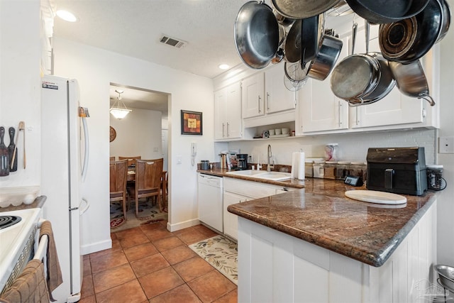 kitchen featuring sink, white cabinets, white appliances, dark stone countertops, and light tile patterned floors