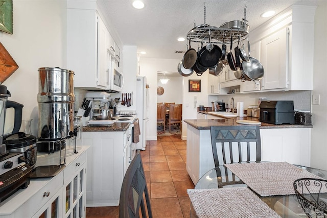 kitchen featuring a textured ceiling, white cabinetry, light tile patterned flooring, and kitchen peninsula