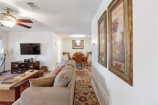 tiled living room featuring ceiling fan and a textured ceiling