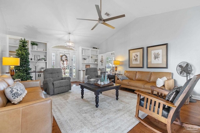 living room featuring ceiling fan, built in features, wood-type flooring, and lofted ceiling