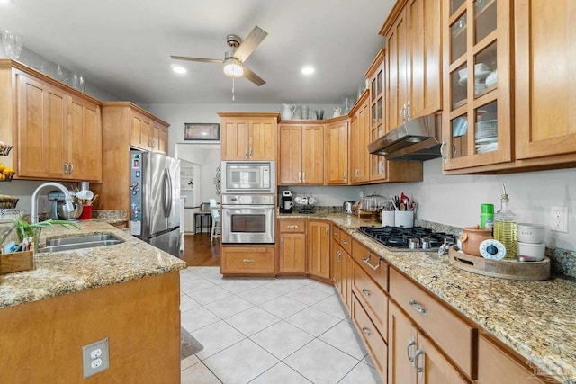 kitchen featuring light stone counters, stainless steel appliances, ceiling fan, sink, and light tile patterned floors