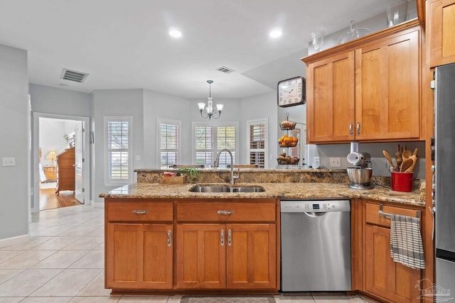 kitchen with light stone countertops, stainless steel appliances, sink, a chandelier, and hanging light fixtures