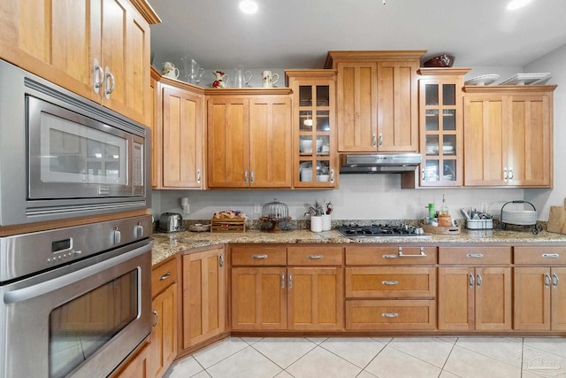 kitchen featuring light tile patterned floors, light stone countertops, and appliances with stainless steel finishes