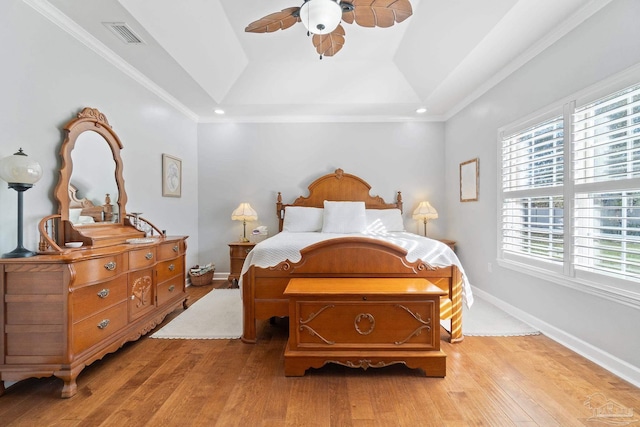 bedroom featuring light wood-type flooring, a tray ceiling, ceiling fan, and ornamental molding