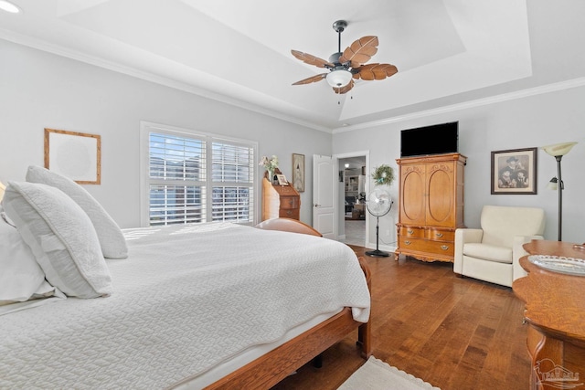 bedroom with ceiling fan, dark hardwood / wood-style floors, crown molding, and a tray ceiling