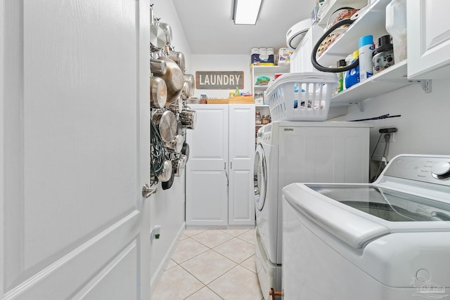 laundry area with washer and dryer, cabinets, and light tile patterned floors