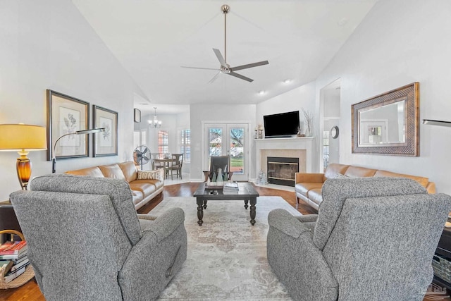 living room with built in features, ceiling fan with notable chandelier, high vaulted ceiling, and light hardwood / wood-style flooring