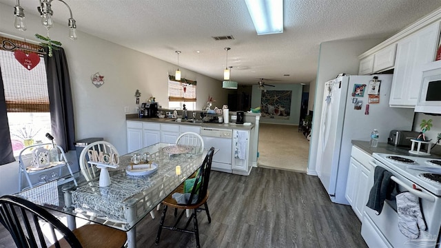 kitchen with white appliances, a peninsula, white cabinets, a textured ceiling, and dark wood-style floors
