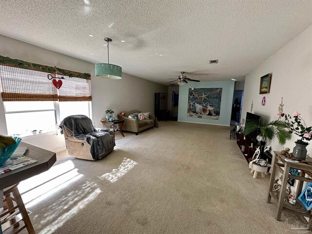 carpeted living area with ceiling fan and a textured ceiling