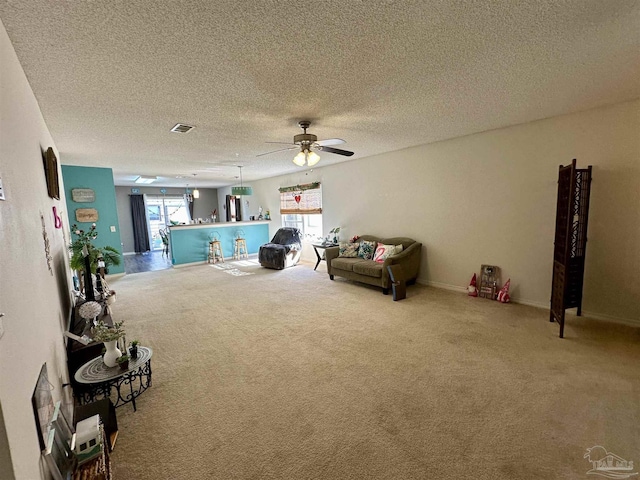 living room with a ceiling fan, carpet floors, and a textured ceiling