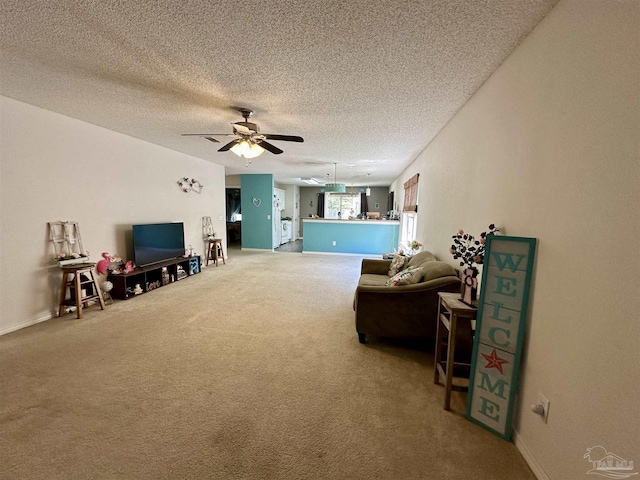 living area with carpet floors, ceiling fan, a textured ceiling, and baseboards