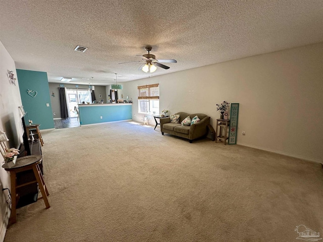 living room featuring carpet floors, ceiling fan, a textured ceiling, and baseboards