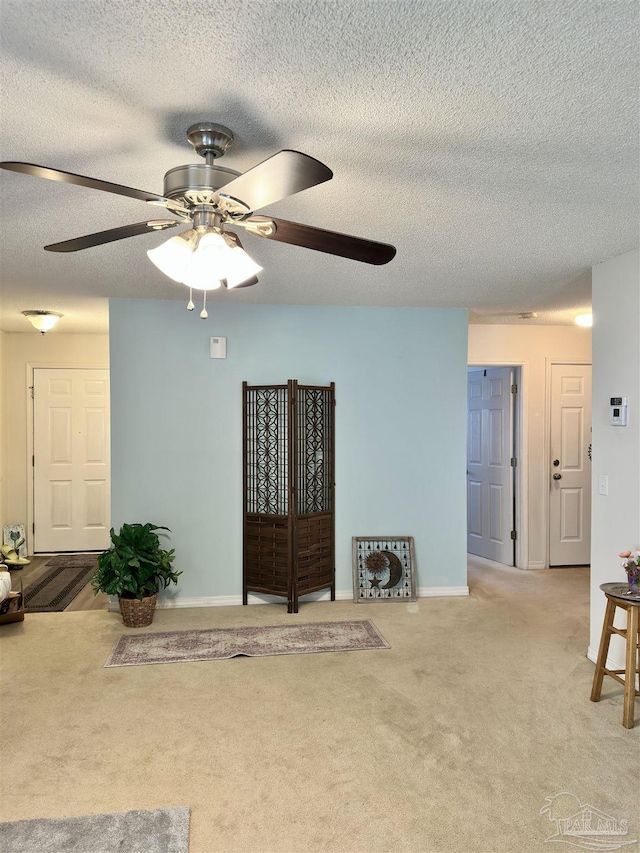 carpeted living room with a ceiling fan, a textured ceiling, and baseboards