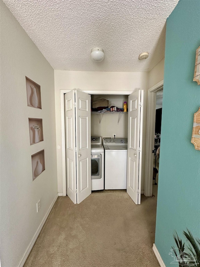 laundry area featuring washer and dryer, light carpet, and a textured ceiling