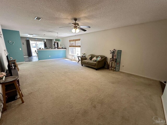 living area featuring carpet flooring, ceiling fan, healthy amount of natural light, baseboards, and a textured ceiling
