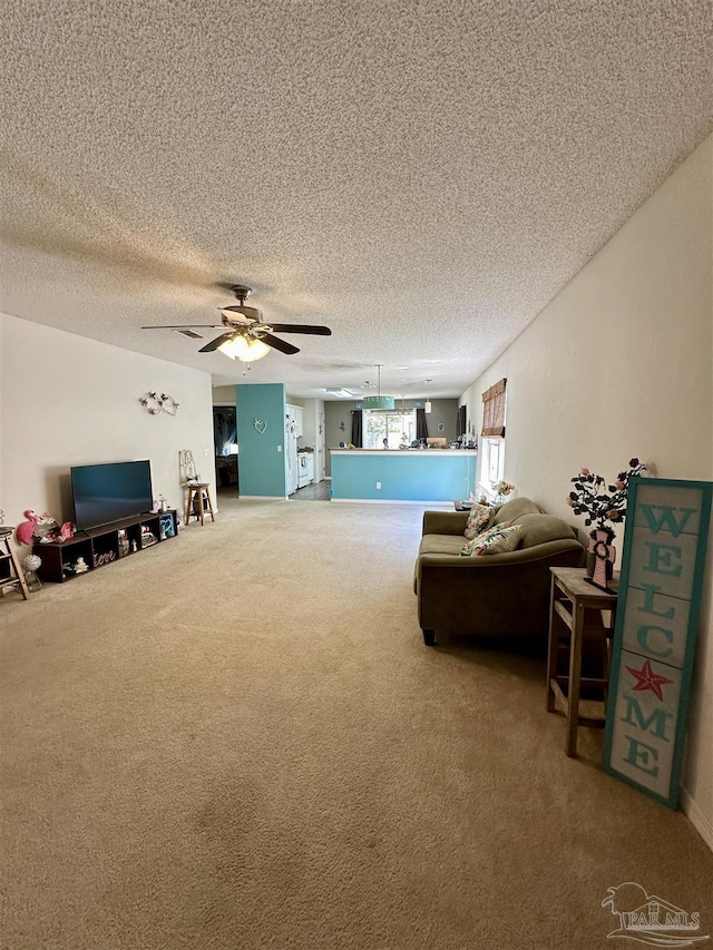 carpeted living area with a ceiling fan and a textured ceiling