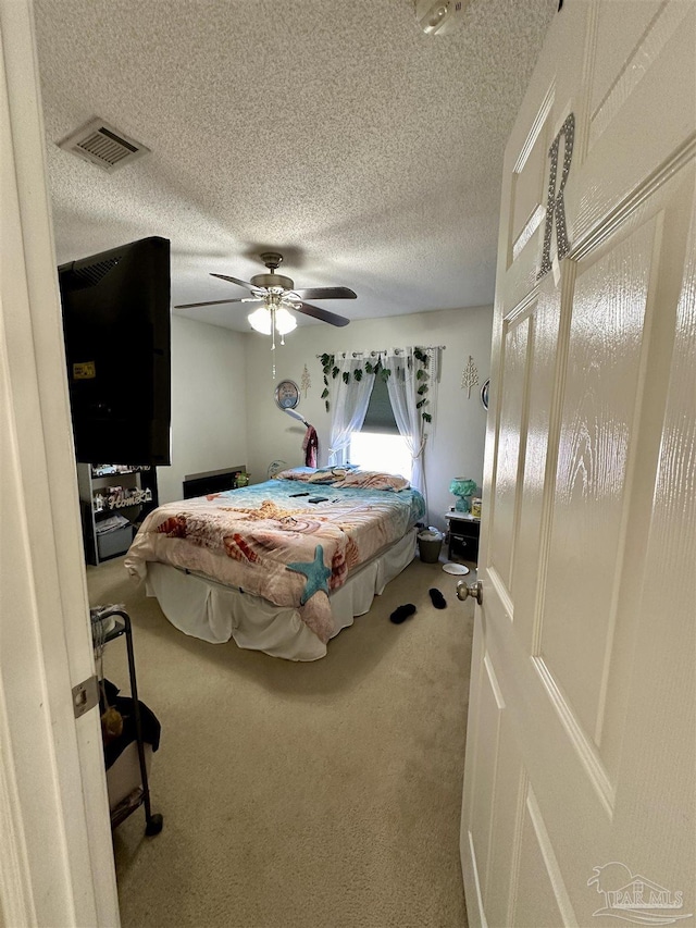 carpeted bedroom featuring a textured ceiling and ceiling fan