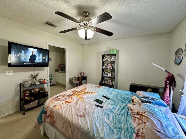 bedroom featuring light carpet, a textured ceiling, ceiling fan, and ensuite bath