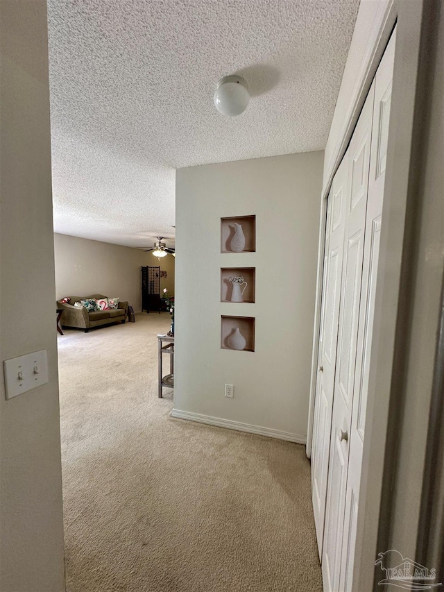 corridor featuring carpet floors, a textured ceiling, and built in features
