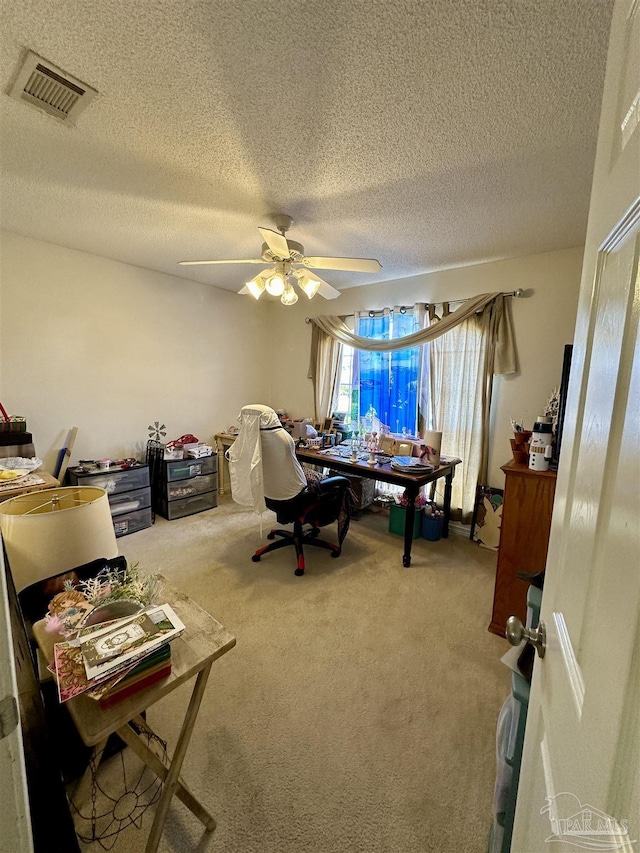 carpeted office space featuring a ceiling fan and a textured ceiling