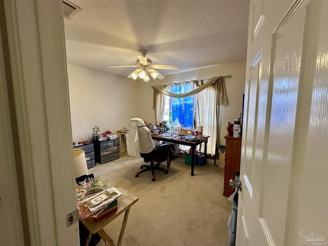 home office with carpet, a ceiling fan, and a textured ceiling