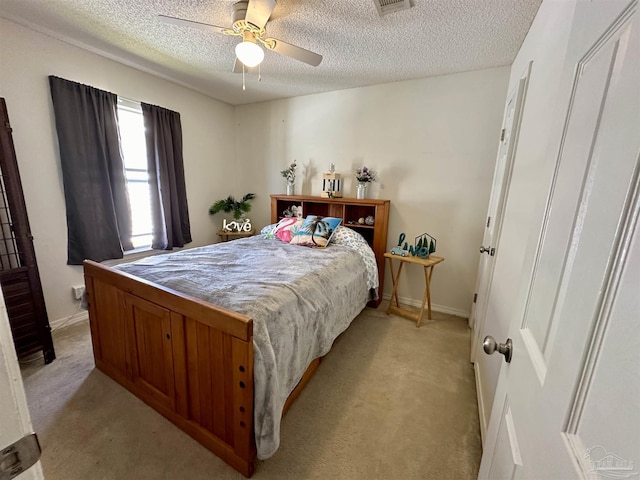 bedroom featuring light carpet, a textured ceiling, ceiling fan, and baseboards