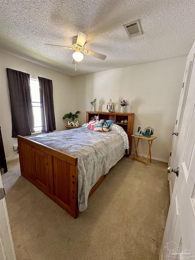 bedroom featuring light colored carpet, a ceiling fan, and a textured ceiling