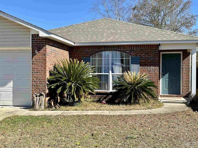 view of exterior entry featuring brick siding, roof with shingles, and an attached garage