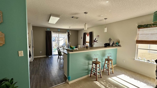 kitchen featuring a textured ceiling, baseboards, a breakfast bar, and pendant lighting