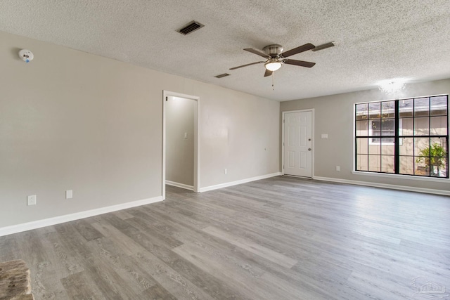 unfurnished room featuring visible vents, baseboards, wood finished floors, a textured ceiling, and a ceiling fan