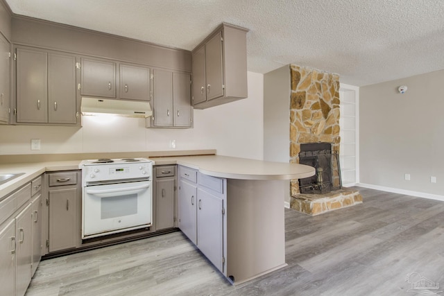 kitchen featuring a peninsula, electric range, light wood-style flooring, light countertops, and under cabinet range hood