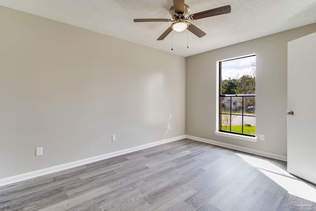 spare room featuring a ceiling fan, wood finished floors, baseboards, and a textured ceiling