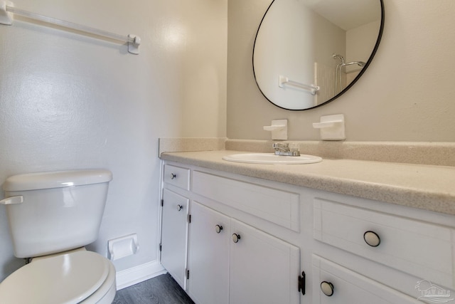 bathroom featuring toilet, vanity, baseboards, and wood finished floors