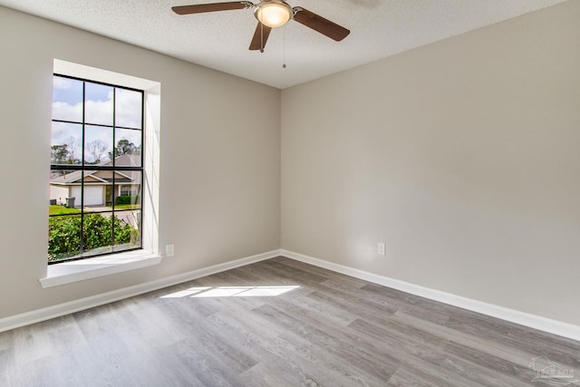 spare room featuring ceiling fan, wood finished floors, baseboards, and a textured ceiling