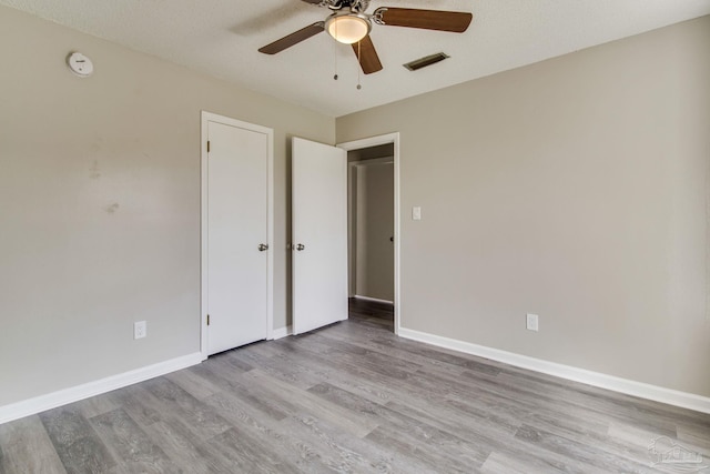 unfurnished bedroom featuring ceiling fan, visible vents, baseboards, and wood finished floors