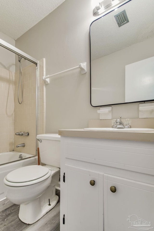 bathroom with a textured ceiling, wood finished floors, vanity, and toilet