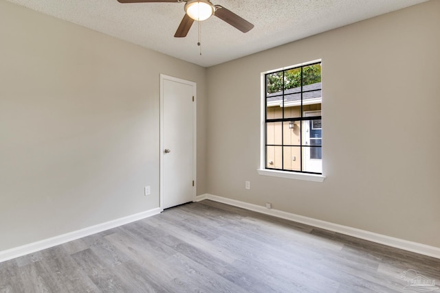 empty room featuring a textured ceiling, baseboards, and wood finished floors