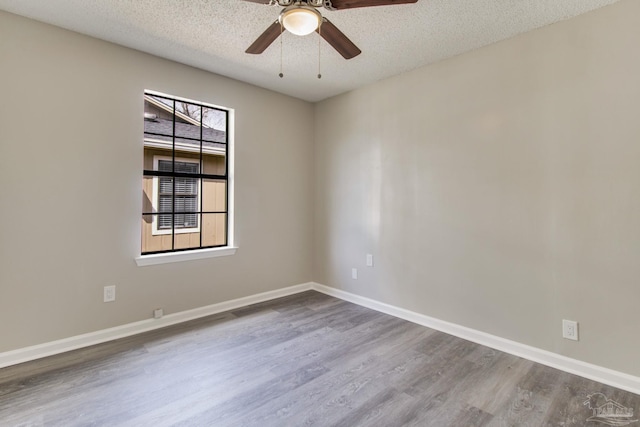 spare room with ceiling fan, baseboards, a textured ceiling, and wood finished floors