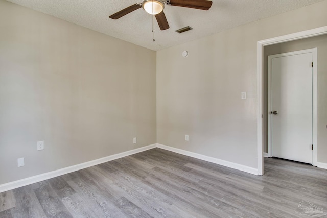 unfurnished room featuring visible vents, a textured ceiling, baseboards, and wood finished floors