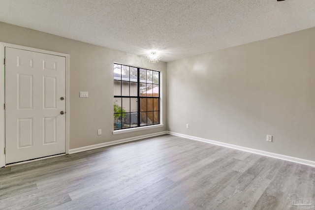 interior space featuring baseboards, a textured ceiling, and wood finished floors