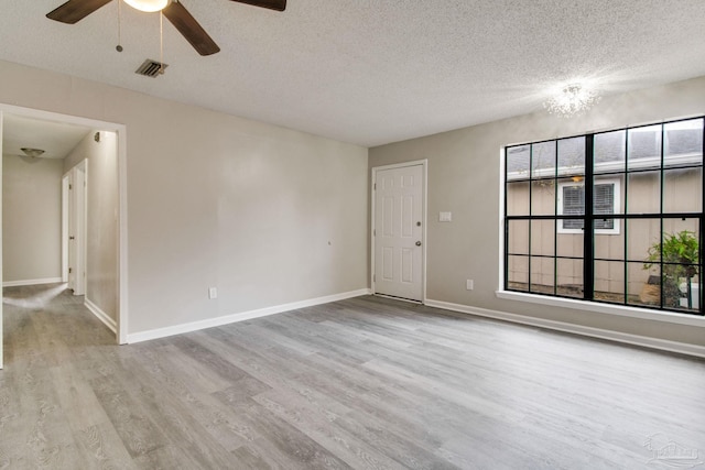 unfurnished room with visible vents, a healthy amount of sunlight, baseboards, and wood finished floors