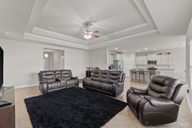 living room featuring a tray ceiling, baseboards, and ceiling fan