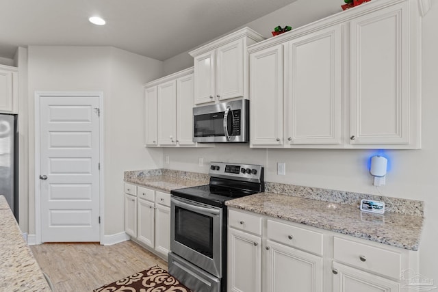 kitchen featuring light stone countertops, recessed lighting, light wood-style floors, appliances with stainless steel finishes, and white cabinetry