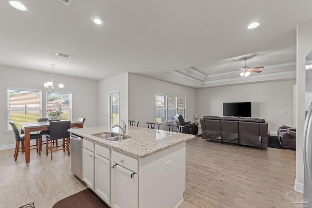 kitchen with an island with sink, a sink, light wood-type flooring, and stainless steel dishwasher