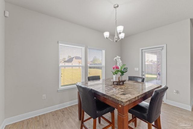 dining space with plenty of natural light, light wood-style flooring, and an inviting chandelier