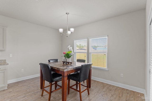 dining space featuring light wood-style floors, baseboards, and a chandelier